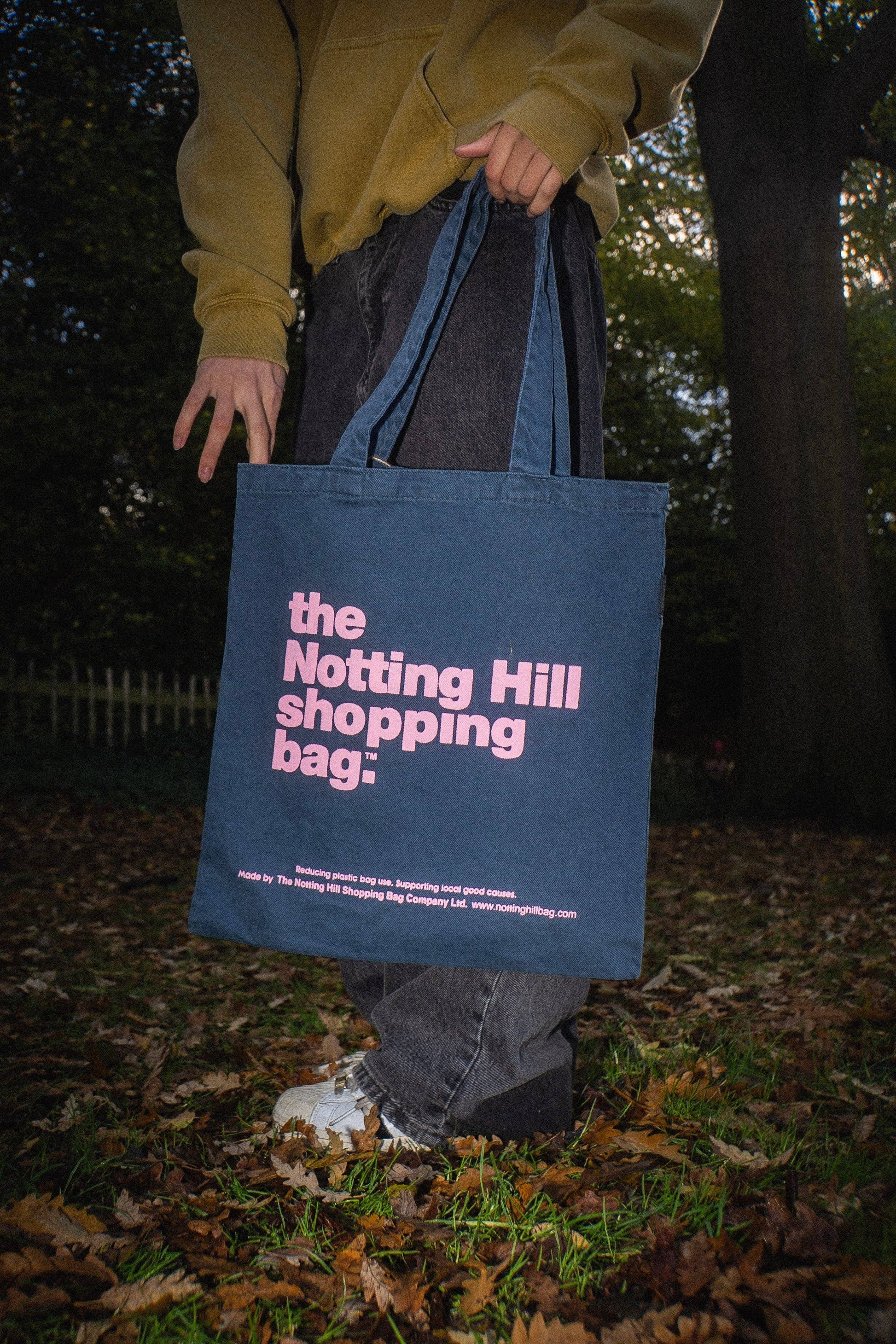 a person holding a Notting Hill Shopping Bag, in Blue basic denim range, with pink writing