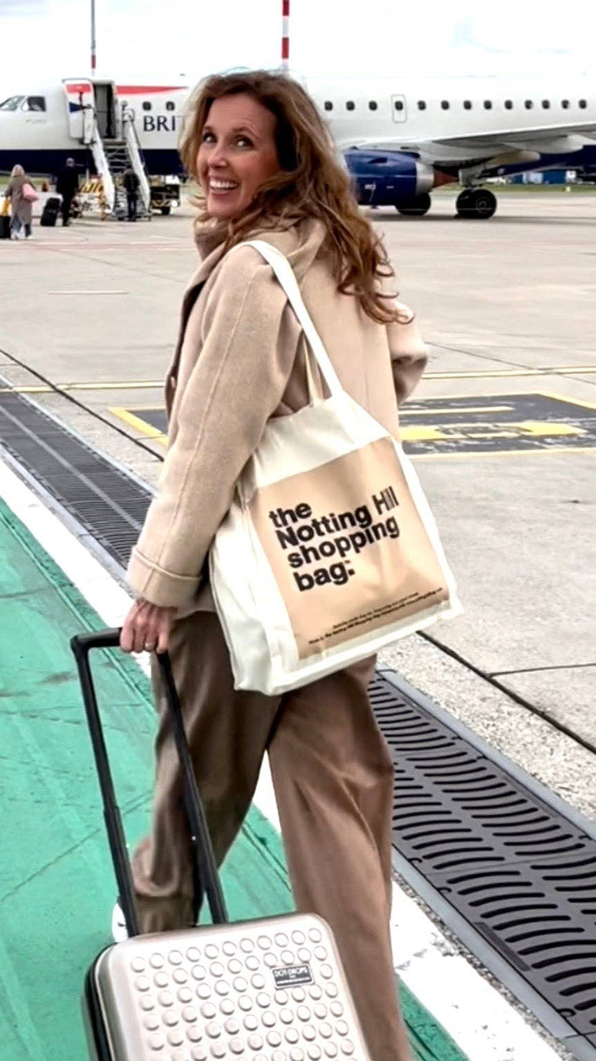 A woman getting on a plane, carrying a Notting Hill Shopping Bag, Beige colour block  range bag