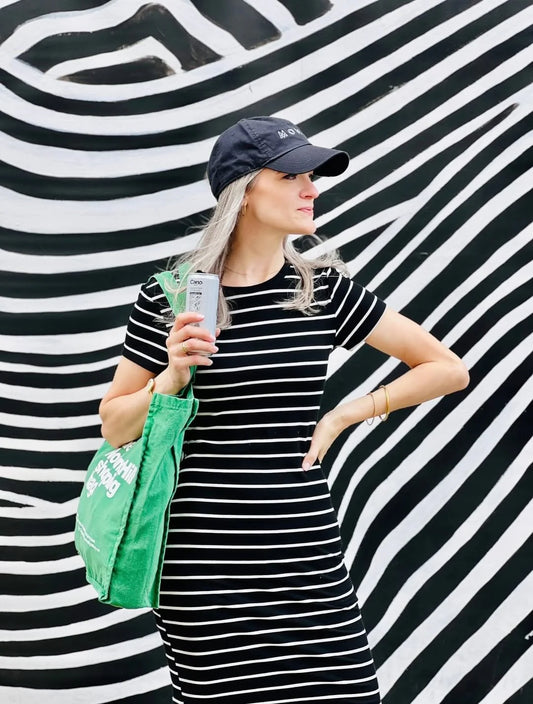 A Notting hill shopping bag, form the hand dye collection, in green, being held by a woman in black and white