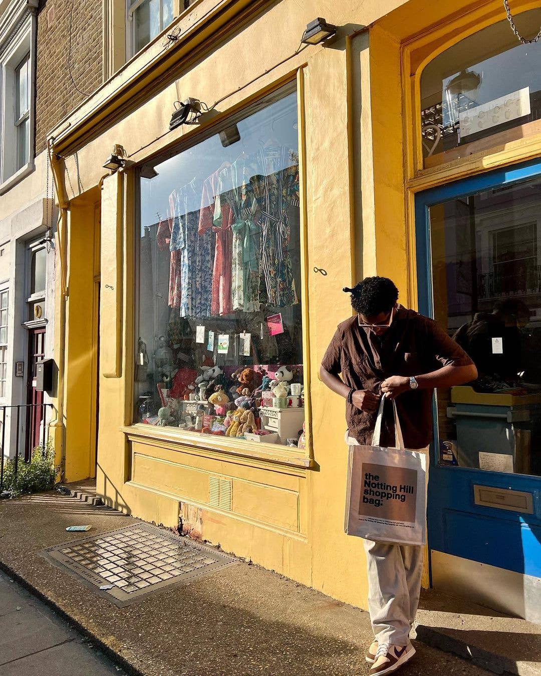 guy Infront of shop, holding a Notting Hill Shopping Bag, Beige Colour Block range, on Portobello Rd, Notting Hill