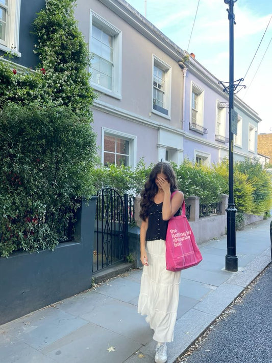A girl on a London street, holding a Notting Hill shopping bag hand dye collection bag, in Pink with ink logo