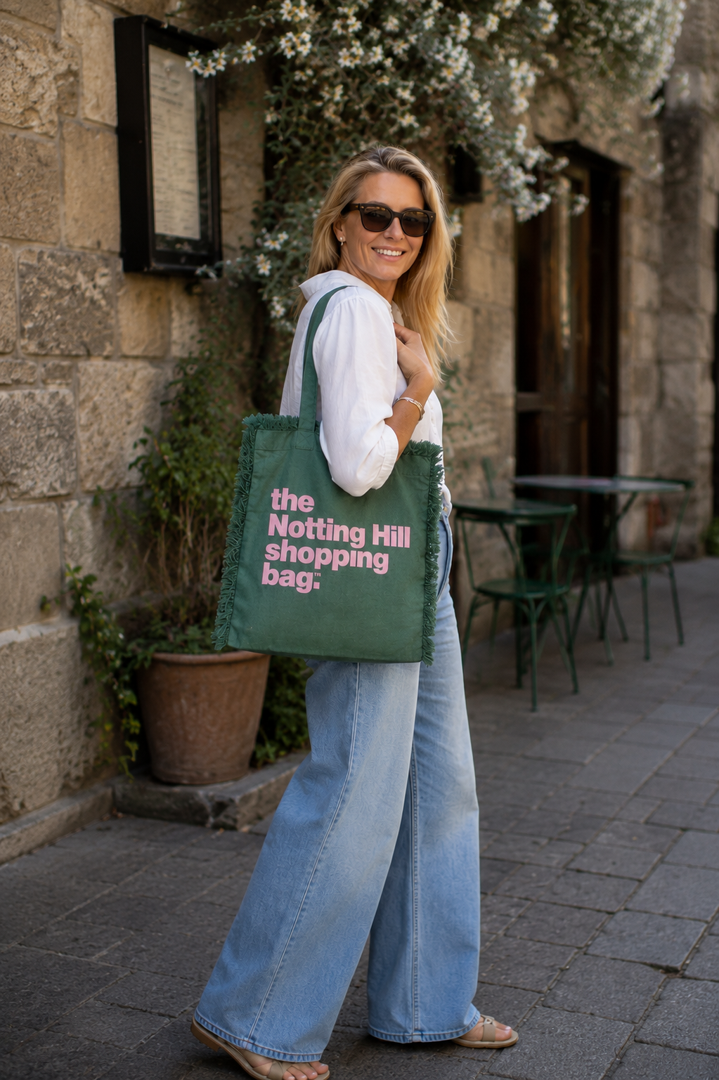 a woman carrying a gren freyed notting hill shopping bag on a casual street