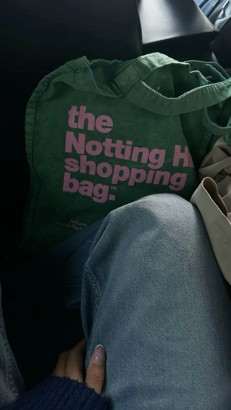 A Notting hill shopping bag, from the hand dye collection, in green with pink logo, in a car