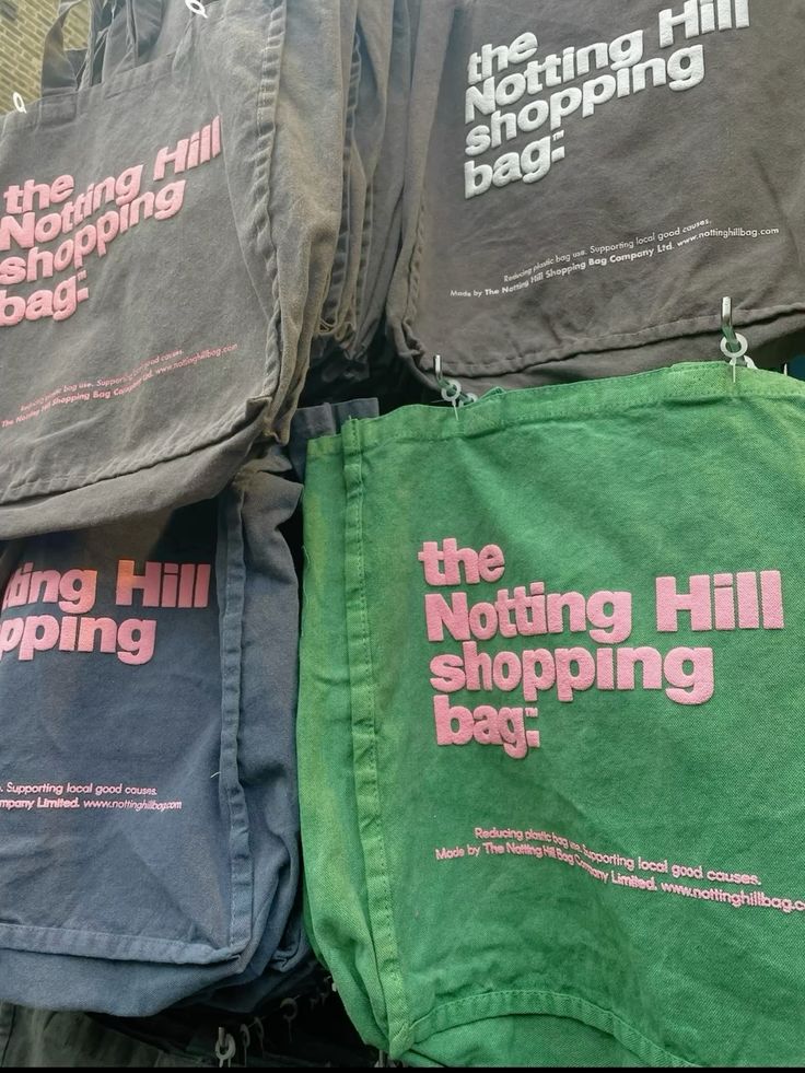 A wall display of notting hill shopping bags from the hand dye collection, with green, navy, and two grey bags