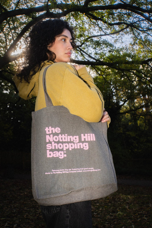a woman in a park, holding a Notting Hill Shopping Bag , from the hand dye collection, in Grey with Pink logo